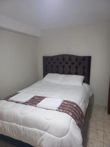 a white bed with a black headboard and white sheets at Ataraxia Light House in Cusco