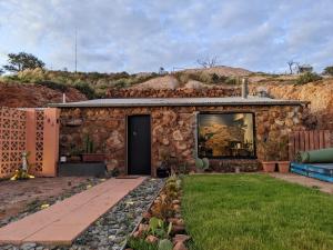 a stone building with a door and a grass yard at Daybreak Dugout Luxury Underground House in White Cliffs