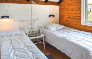 a bedroom with two beds and a chair in it at Nice Home In Thisted With 3 Bedrooms, Sauna And Wifi in Nørre Vorupør