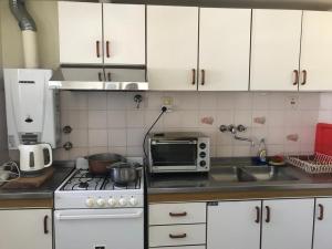 a kitchen with white cabinets and a stove and a microwave at AMPLIO Y LUMINOSO in Concordia
