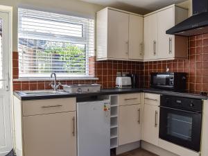 kuchnia z białymi szafkami i kuchenką mikrofalową w obiekcie Mutley Hall w mieście Eastergate