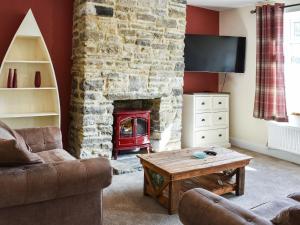 sala de estar con chimenea, sofá y mesa en Woodside Cottage, en Low Etherley