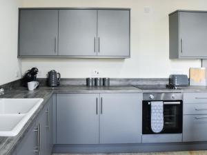 cocina con armarios blancos y lavavajillas negro en Woodside Cottage, en Low Etherley