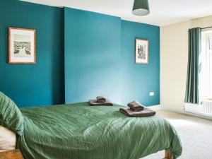 a bedroom with blue walls and a bed with towels on it at Woodside Cottage in Low Etherley