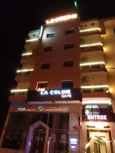 un palazzo alto con un cartello di notte di Hotel La coline a Beni Mellal