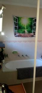 a bath tub in a bathroom with a painting on the wall at Frances's home in Gilles Plains