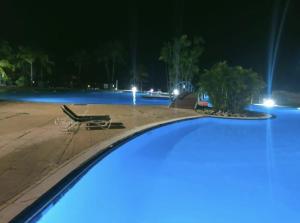 - une vue sur la piscine la nuit avec une chaise dans l'établissement Studio cosy, vue sur mer villages vacances Sainte anne chèques vacances acceptés, à Sainte-Anne