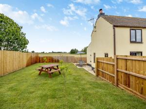 a backyard with a wooden fence and a picnic table at Huntspill Cottage in Holbeach