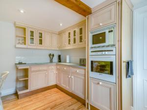 cocina con armarios blancos y horno en The Stirrup Cottage en Blyborough