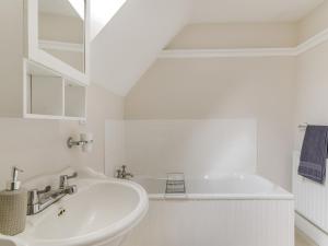 a white bathroom with a sink and a tub at The Stirrup Cottage in Blyborough