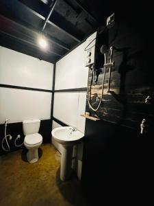 a black and white bathroom with a toilet and a sink at hornbill river camp udawalwa in Udawalawe