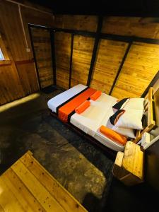 a bed in a room with a wooden wall at hornbill river camp udawalwa in Udawalawe