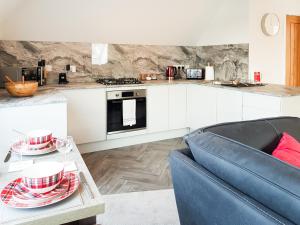 a kitchen with white cabinets and a blue couch at Palace View - Uk40569 in Falkland