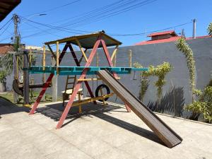 a wooden play structure with a slide in front of a building at Casa amarela 2km de Geribá-Buzios in Búzios