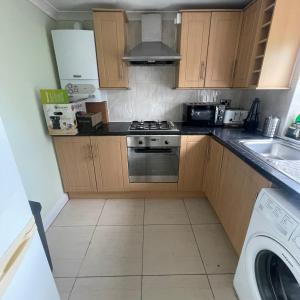 a kitchen with wooden cabinets and a stove top oven at Entire 3 BR Home - Minutes to Emirates Stadium! in London