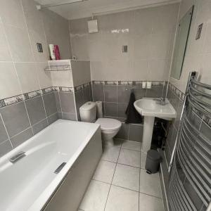 a bathroom with a tub and a toilet and a sink at Entire 3 BR Home - Minutes to Emirates Stadium! in London