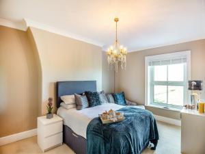1 dormitorio con cama y lámpara de araña en Jacks House- Uk40741, en Tywyn