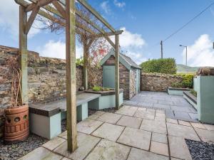 un patio con banco y pared de piedra en Jacks House- Uk40741 en Tywyn