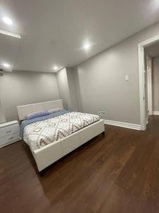 ein weißes Schlafzimmer mit einem Bett und Holzboden in der Unterkunft Guest Suite in Oakville in Oakville