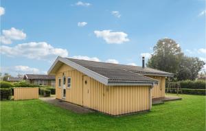 um pequeno edifício amarelo num quintal com relva em Beautiful Home In Odder With 4 Bedrooms And Wifi em Norsminde