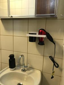 lavabo en el baño con secador de pelo en la pared en Confortável, Equipado e Bem Localizado c/ Garagem, en Curitiba