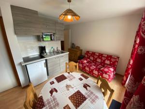 eine Küche mit einem Tisch und einer roten Couch in einem Zimmer in der Unterkunft Charmant 2 pièces avec terrasse et parking proche des pistes à La Chapelle-d'Abondance - FR-1-692-89 in La Chapelle-dʼAbondance