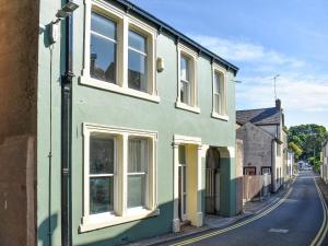 a green building with white windows on a street at South Street House in Cockermouth