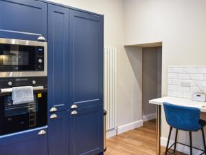 a blue kitchen with a stove and a blue chair at South Street House in Cockermouth