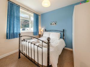 a bedroom with a bed with blue walls and a window at Awesome Cottage In Cilau Aeron, Near Lampeter With 2 Bedrooms And Wifi in Ciliau-Aeron