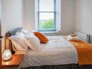 uma cama com almofadas cor-de-laranja e brancas e uma janela em Invergyle - Uk40566 em Ilhas Malvinas