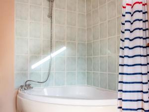 a bathroom with a tub and a shower curtain at Hen Efail - Old Smithy in Tregaron