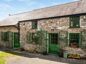 - un vieux bâtiment en pierre avec des portes et des fenêtres vertes dans l'établissement Hen Efail - Old Smithy, à Tregaron