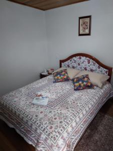 1 dormitorio con 1 cama con edredón y almohadas en Pousada Vivenda das Flores Ltda, en Bom Jardim da Serra