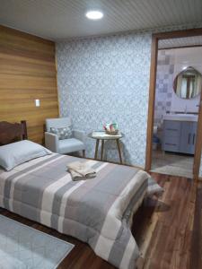 a bedroom with a bed and a chair and a sink at Pousada Vivenda das Flores Ltda in Bom Jardim da Serra