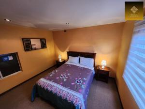 a bedroom with a bed with a purple blanket at Hostal Mirador Quellón in Quellón