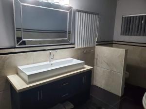 een badkamer met een witte wastafel en een spiegel bij The Palms- Caribbean Estates -10 minutes from the beach- Gated Community in Portmore