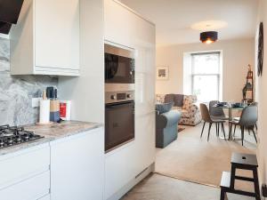 uma cozinha com armários brancos e uma sala de estar em Liquorstane - Uk40568 em Falkland