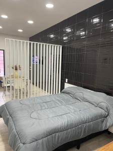 1 dormitorio con 1 cama y una pared de azulejos negros en Espectacular Departamento moderno ,acogedor en vicente López en Vicente López