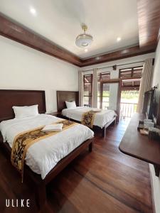 a hotel room with two beds and a television at Namkhan Riverview Boutique House in Luang Prabang