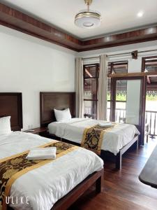 a hotel room with two beds and a balcony at Namkhan Riverside Hotel in Luang Prabang