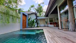 a house with a swimming pool and a wooden deck at The Decks Bali in Legian