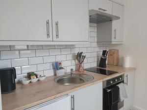 encimera de cocina con fregadero y armarios blancos en Flat 7 - Newly Renovated, en Portsmouth