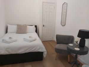 a white bedroom with a bed and a chair at Flat 7 - Newly Renovated in Portsmouth