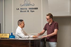 twee mannen die handen schudden voor een tafel bij La Renta Premier Hotel & Spa Hanoi in Hanoi