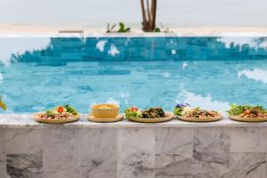 uma fila de pratos numa mesa ao lado de uma piscina em Luxury Penthouse - Khanom em Ban Plau