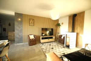 uma sala de estar com uma televisão e um sofá e cadeiras em Magnifique Maison de plain-pied Neuf 