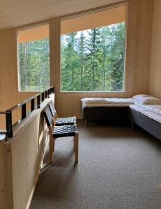 a room with two beds and a bench and two windows at Havu Resort Laajavuori, a calm and peasefull place in the forest near city in Jyväskylä