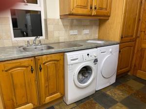 a kitchen with a washing machine and a sink at Bushtown Lodge in Macosquin