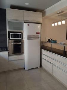 Una cocina con un refrigerador blanco y un microondas. en Moderno Duplex 2 - Alquiler en Comodoro Rivadavia, en Comodoro Rivadavia