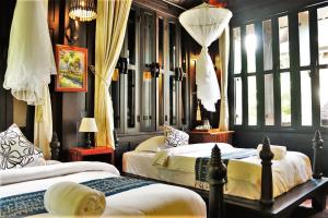 um quarto com 2 camas com cortinas e janelas em Namkhan View Luangprabang Resort em Luang Prabang
